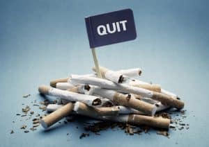 close up of part used cigareetes and a flag saying quit sticking out of the pile