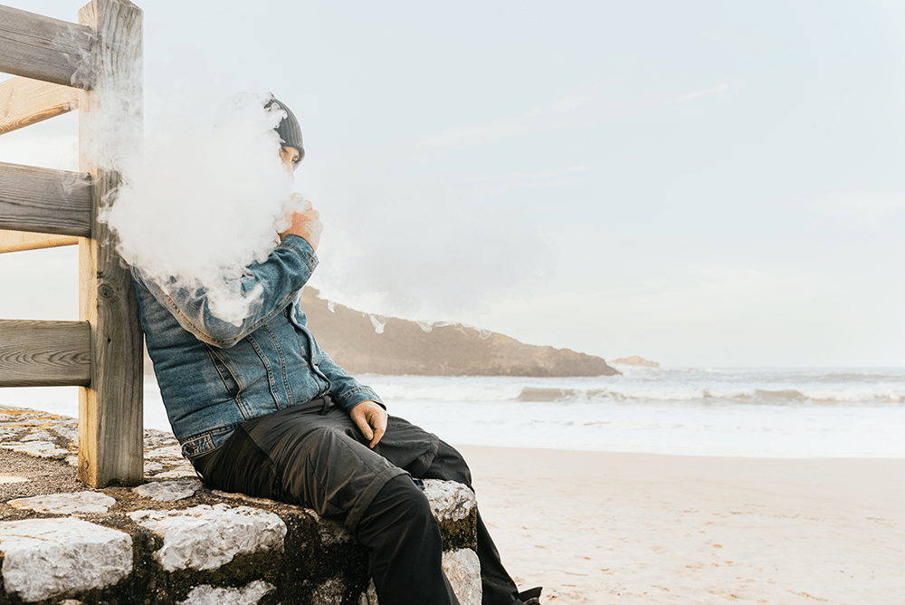 Man smoking an e-cigarette at the beach